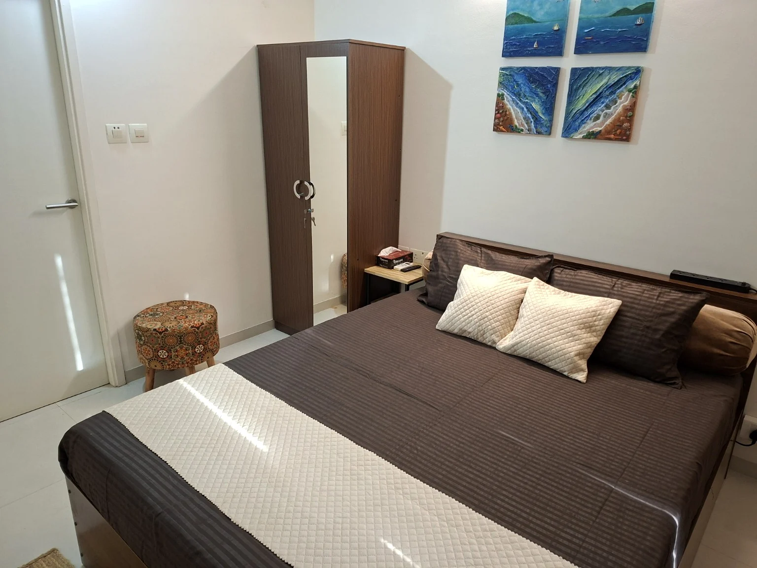 Mirrored wardrobe beside the bed and a patterned stool