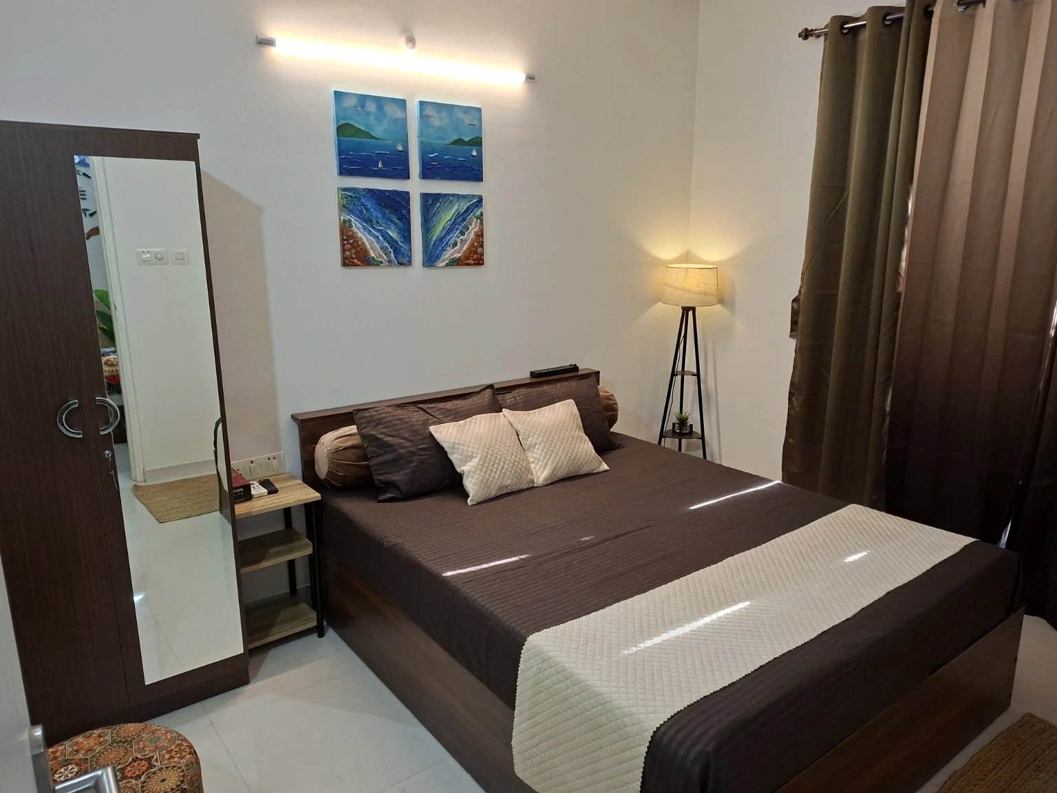 Bedroom with a double bed, bedside lamp and sea-inspired artwork