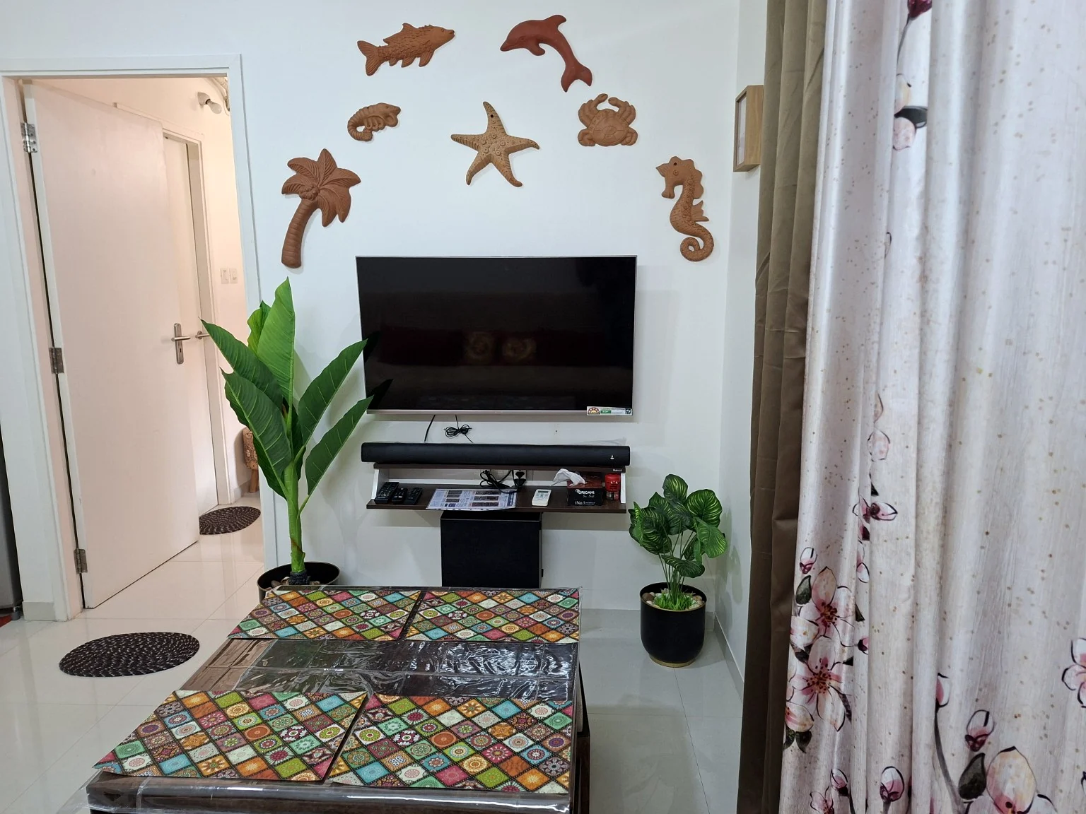 Wall-mounted TV and boAt soundbar, with wooden sea-life decorations above