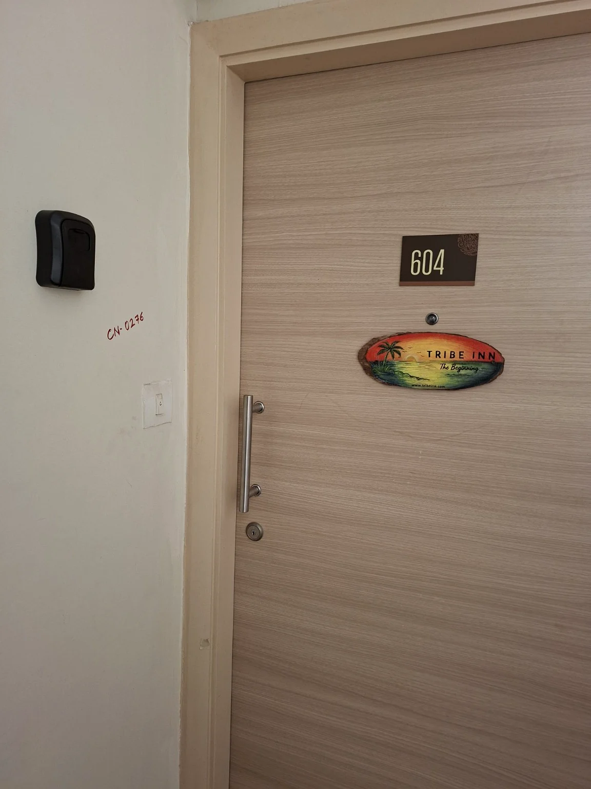 Apartment entrance with the original Tribe Inn The Beginning wooden sign